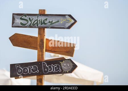 Holzpfosten mit Kopierbereich am Strand. Pfeile auf einem Führungsposten, die auf das Meer zeigen. Wegweiser Stockfoto