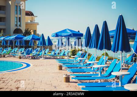 Blaue Sonnenschirme und Sonnenliegen in der Nähe des Pools im Sommerresort. Bulgarien Duni. Sommerferien Stockfoto