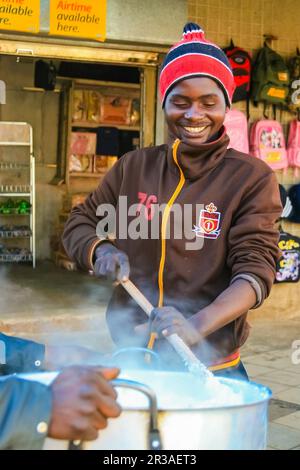 Junger afrikanischer Mann, der Mielie Pap Maisporridge in einer Seitenstraße in Soweto kocht Stockfoto