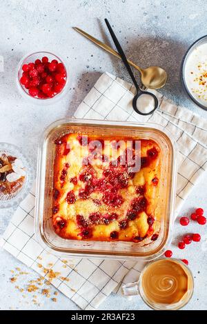 Hüttenkäse-Auflauf mit roten Johannisbeeren. Auflauf mit frischen Beeren auf dem Küchentisch Stockfoto