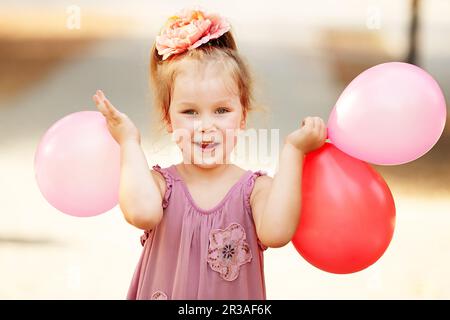 Portrait von lachendem und spielendem kleinen Mädchen mit bunten Ballons. Positive Emissionen. Fröhliches Chi Stockfoto
