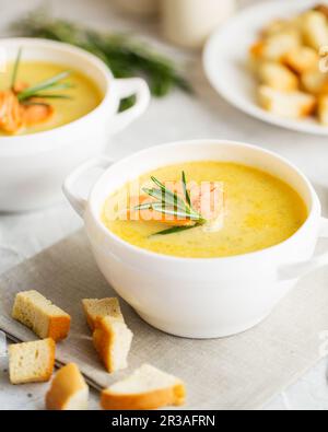 Fischsahnesuppe mit Lachs, Käse, Kartoffeln und Kräutern in weißen Suppenschalen. Stockfoto