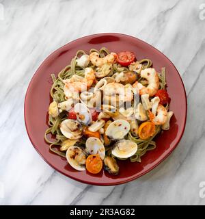 Mediterrane Meeresfrüchte, Weißwein, Garnelen, Muscheln, Muscheln, Calamari, Tomaten auf weißem Teller Stockfoto
