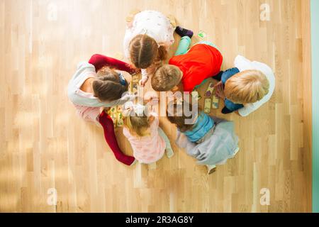 Gruppe von Kindern, die auf einem Stockwerk pädagogische Karten spielen. Puzzle mit Tieren Mutter und Baby. Stockfoto