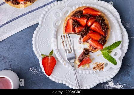 Minitarte mit Erdbeermarmelade, serviert mit frischen Erdbeeren und Schokoladenganache Stockfoto