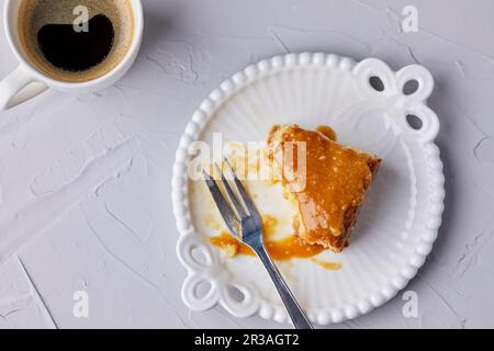 Halb gegessen Tres Leches Kuchen, bedeckt mit Karamellsauce und verstreut mit Meersalz Stockfoto