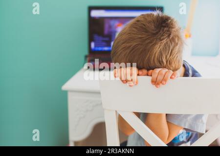 Der Junge sitzt zu Hause und vermisst das übliche Lernen Stockfoto