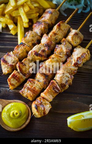 Griechisches Souvlaki serviert mit gebratenen Kartoffeln und Senfsauce Stockfoto