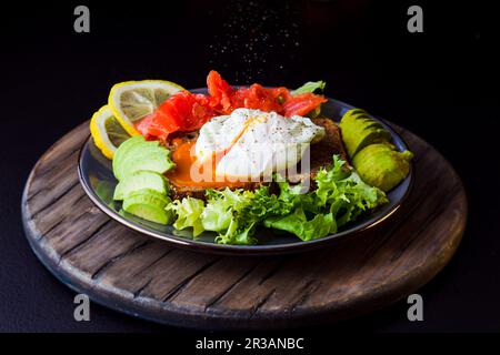 Teller mit Eier auf Brot mit Lachs und Gemüse serviert Stockfoto