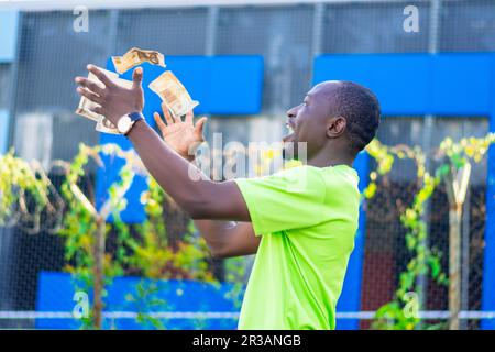 Überglücklich, junger Mann mit erhobener Faust, die den Zahltag feiert, aufgeregt auf Erfolg, da viel Geld aus der Luft fällt. Wirtschaft und Finanzen, Verdienst Mo Stockfoto