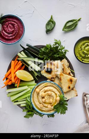 Verschiedene Arten von Hummus serviert mit frischem Gemüse und Pita-Brot Stockfoto