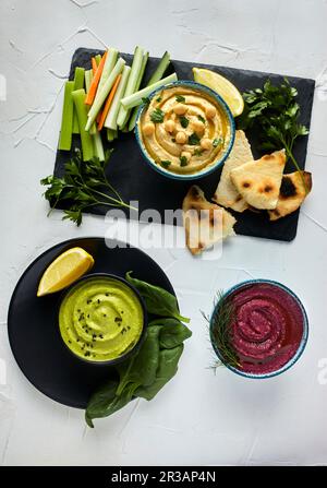 Verschiedene Arten von Hummus serviert mit frischem Gemüse und Pita-Brot Stockfoto