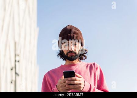 Eleganter junger Mann, der auf seinem Smartphone SMS schreibt Stockfoto