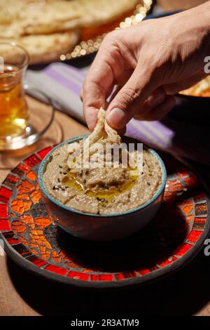 Ein Stück Brot in Baba Ghanoush Dip tauchen Stockfoto