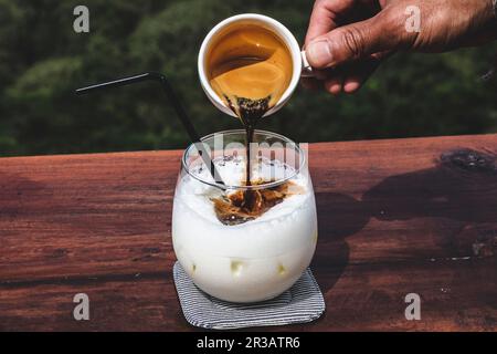 Espresso in einen Eiskaffee gießen Stockfoto