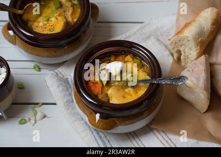 Gemischte Gemüsesuppe, serviert in Tontöpfen, garniert mit gegrilltem Käse und Toast Stockfoto