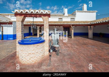 Ein Brunnen mit blauem Deckel in einem Bauernhaus in La Mancha mit einer Metallfigur von Don Quijote, Spanien Stockfoto