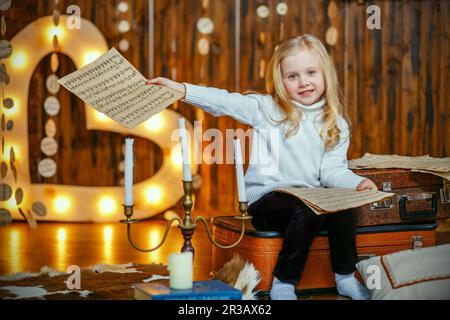 Blonde kleine Mädchen hält eine Notiz im Vintage-Interieur Stockfoto