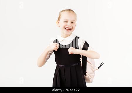 Lustiges lächelndes kleines Mädchen mit großem Rucksack, das vor weißem Hintergrund Spaß hat. Ich Schaue Stockfoto
