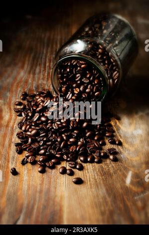 Kaffee Bohnen auf einem Holztisch und in einem Glas Stockfoto