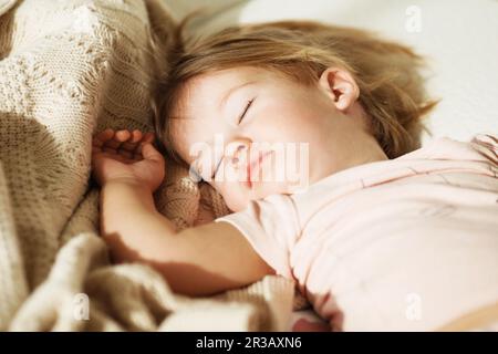 Schlafendes kleines Mädchen. Sorgenfreier Schlaf, kleines Baby, mit einem weichen Spielzeug auf dem Bett. Nahaufnahme Porträt eines Stockfoto