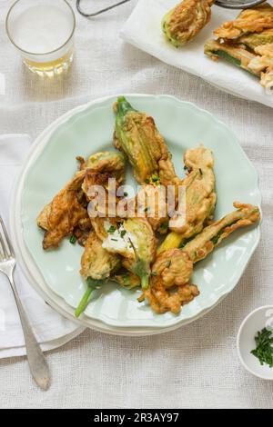 Zucchini-Blumen gefüllt mit Ricotta, gebraten in einem Bierteig, frische Schnittlauch Stockfoto