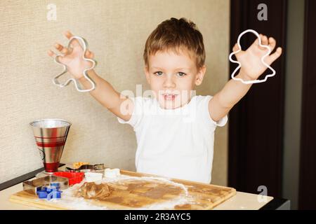 Kinderhände machen Lebkuchen. Ein kleiner Junge, der zu Weihnachten Kekse schneidet. Kid Baking Cooki Kochen Stockfoto