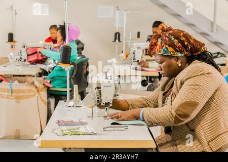 Afrikanische Näherinnen, die mit einer Nähmaschine an handgefertigten Kleidungsstücken arbeiten Stockfoto