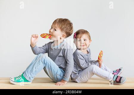 Kleine Kinder, die Lutscher essen. Glückliche Kinder mit großen Süßigkeiten. Porträt eines glücklichen kleinen Kindes. Stockfoto