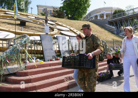 KIEW, UKRAINE - 23. MAI 2023 - Mitglieder der Öffentlichkeit bringen Topfblumen zur Gedenkstätte in der Allee der himmlischen Hundert Helden am Tag des Himmels Stockfoto