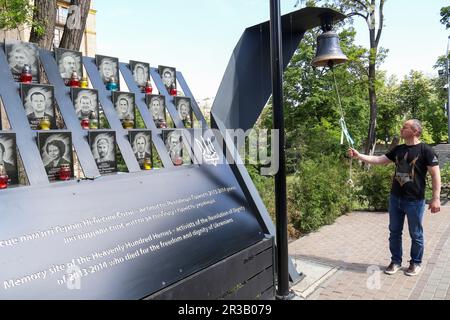 KIEW, UKRAINE - 23. MAI 2023 - Ein Mann läutet die Glocke an der Gedenkstätte für die himmlischen Hundert Helden am Tag der Helden, Kiew, Hauptstadt der Ukraine. Stockfoto
