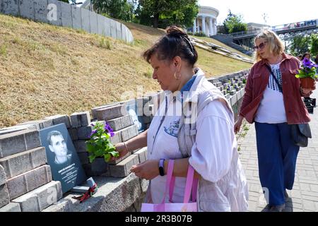 KIEW, UKRAINE - 23. MAI 2023 - Eine Frau hinterlässt Blumen an der Gedenkstätte in der Allee der himmlischen Hundert Helden am Tag der Helden in der Hauptstadt Kiew Stockfoto