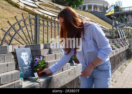 KIEW, UKRAINE - 23. MAI 2023 - Eine Frau hinterlässt Blumen an der Gedenkstätte in der Allee der himmlischen Hundert Helden am Tag der Helden in der Hauptstadt Kiew Stockfoto