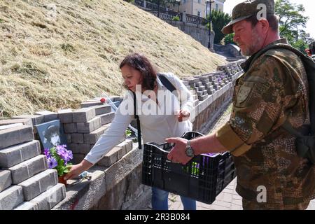 KIEW, UKRAINE - 23. MAI 2023 - Eine Frau hinterlässt Blumen an der Gedenkstätte in der Allee der himmlischen Hundert Helden am Tag der Helden in der Hauptstadt Kiew Stockfoto