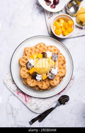 Vegane Vanille-Waffeln mit Mangosorbet, Sojasahne und Obst Stockfoto