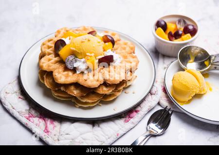 Vegane Vanille-Waffeln mit Mangosorbet, Sojasahne und Obst Stockfoto