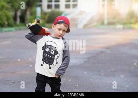 Kleiner Stadtjunge mit einem Penny Skateboard. Ein junger Junge, der auf einem Skateboard im Park reitet. City-Style. Stockfoto