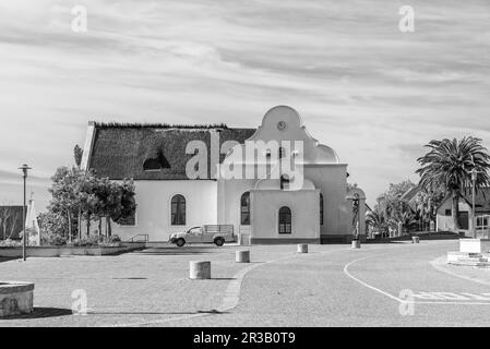 Elim, Südafrika - 21. September 2022: Eine Straßenszene mit der historischen mährischen Kirche in Elim, in der Provinz Westkap. Schwarzweiß Stockfoto