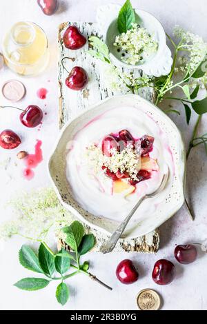 Joghurt mit Holunderblütensirup und Kirschen Stockfoto