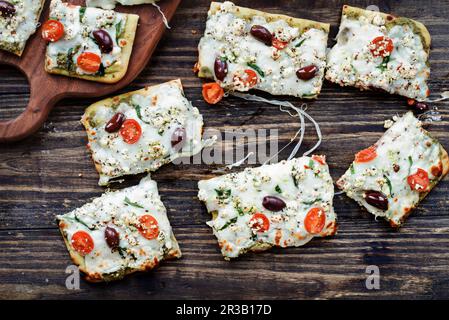 Handwerkliche Pizza mit Mozzarella-Käse, frischen Tomaten, Ziegenkäse, Spinat, kalamata-Oliven und Pesto Stockfoto