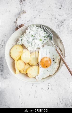 Einfaches vegetarisches Mittagessen. Spiegelei, Bratkartoffeln und Hüttenkäse mit grünen Zwiebeln. Stockfoto