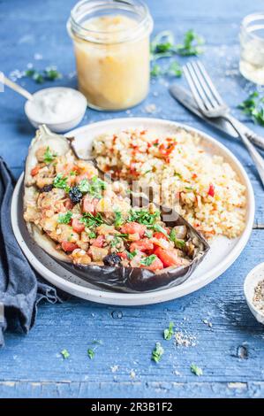 Vegetarische Aubergine gefüllt mit Paprika, Tomaten und Petersilie, serviert mit Bulgur Stockfoto