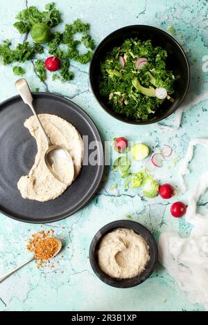 Massierter Grünkohlsalat in einer Schüssel mit Hummus Stockfoto