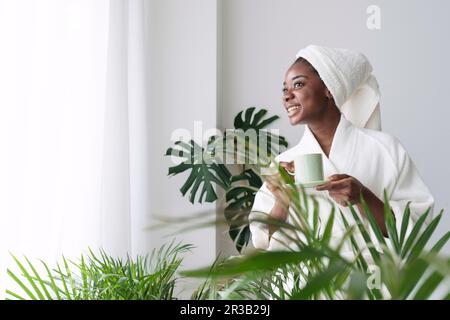 Aufgeregte junge Frau, die zu Hause eine Tasse Kaffee hält Stockfoto