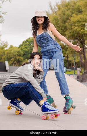 Lächelnde junge Freunde, die Rollschuhe auf dem Fußweg tragen Stockfoto