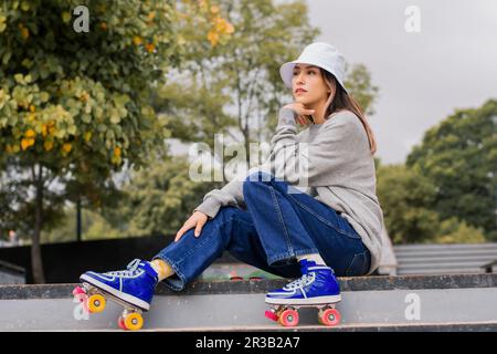 Rücksichtsvolle junge Frau, die auf den Stufen im Park sitzt Stockfoto