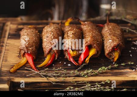 Fleischbrötchen gefüllt mit süßem roten und gelben Paprika auf Ein hölzerner Servierbrett Stockfoto