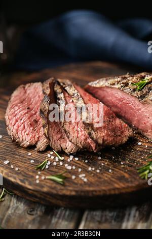 Saftige mittellange Rinderrib Eye-Steaks auf Holzbrett mit Kräutern, Gewürzen und Salz. Fertig zum Stea essen Stockfoto