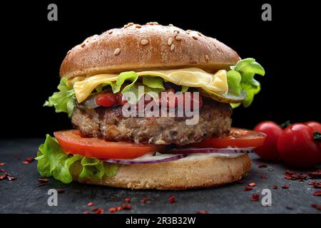 burger mit Fleisch, Käse, Tomaten, Gurken, Ketchup und knusprigem Salat Stockfoto