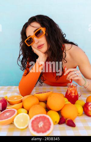 Rücksichtsvolle Frau, die mit Zitrusfrüchten auf dem Tisch trinkt Stockfoto